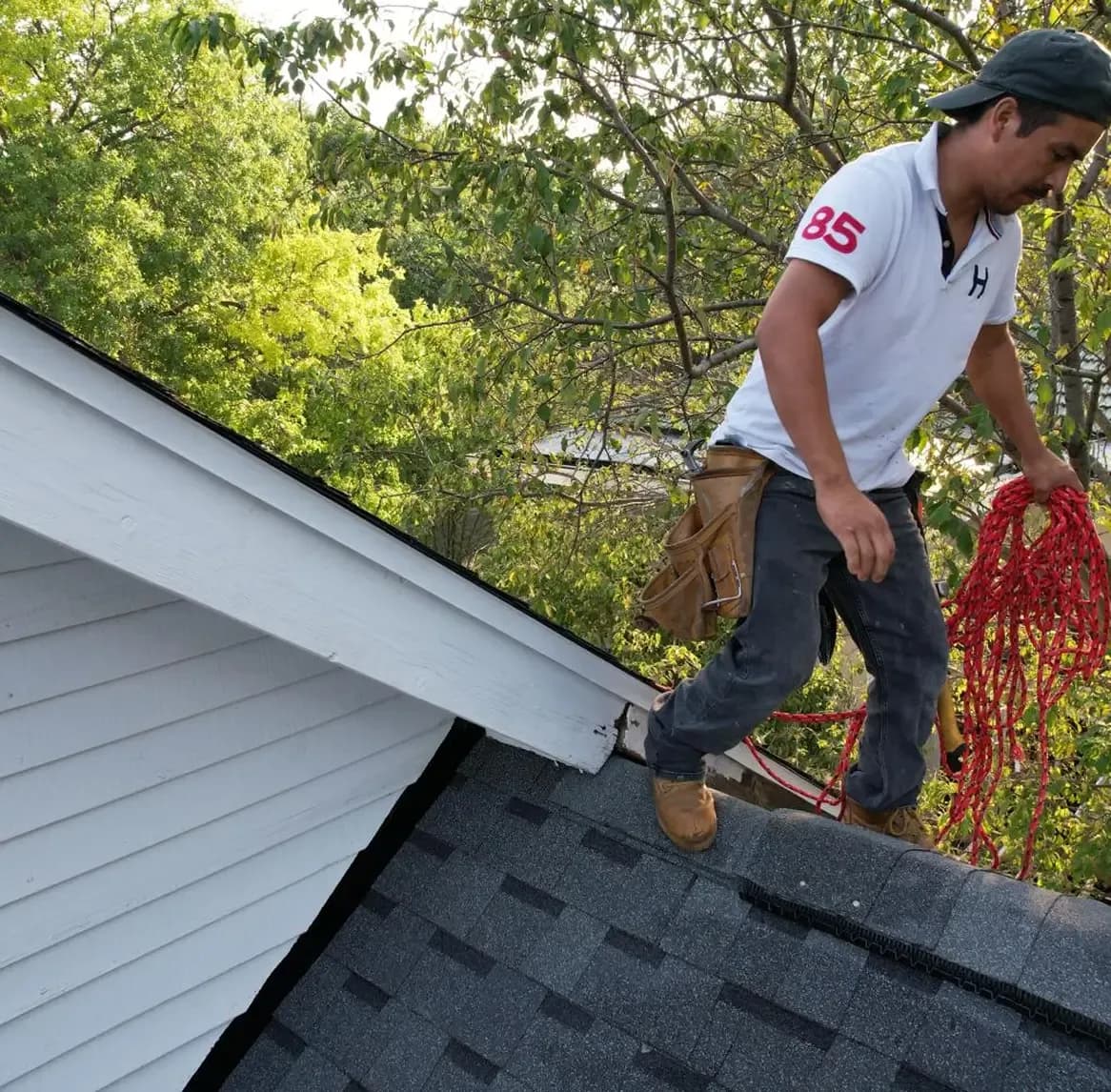 A worker stands on a damaged roof.