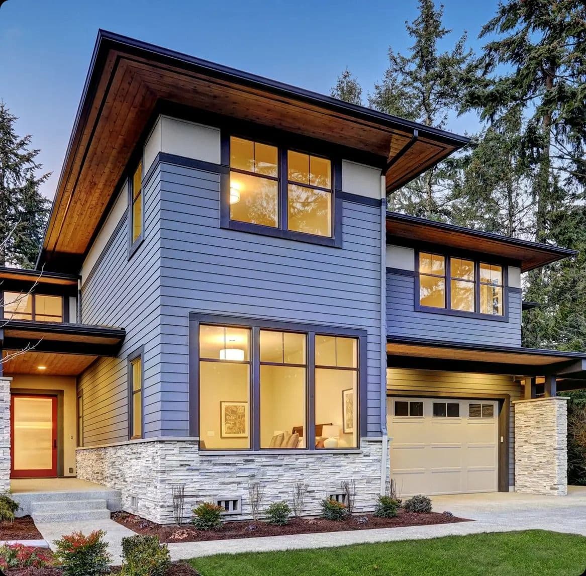 A house with new gray siding and dark trim, and a light stone foundation.