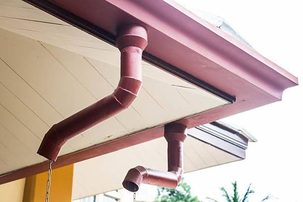 Red K-style gutters on the corner of a house.