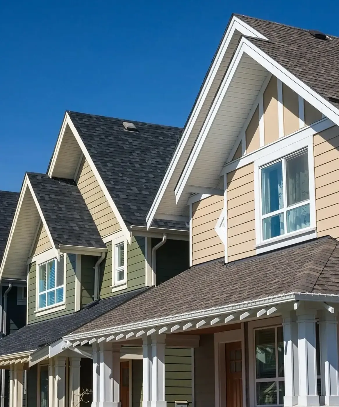 Two homes, one tan, one tan and green, with newly-replaced windows.
