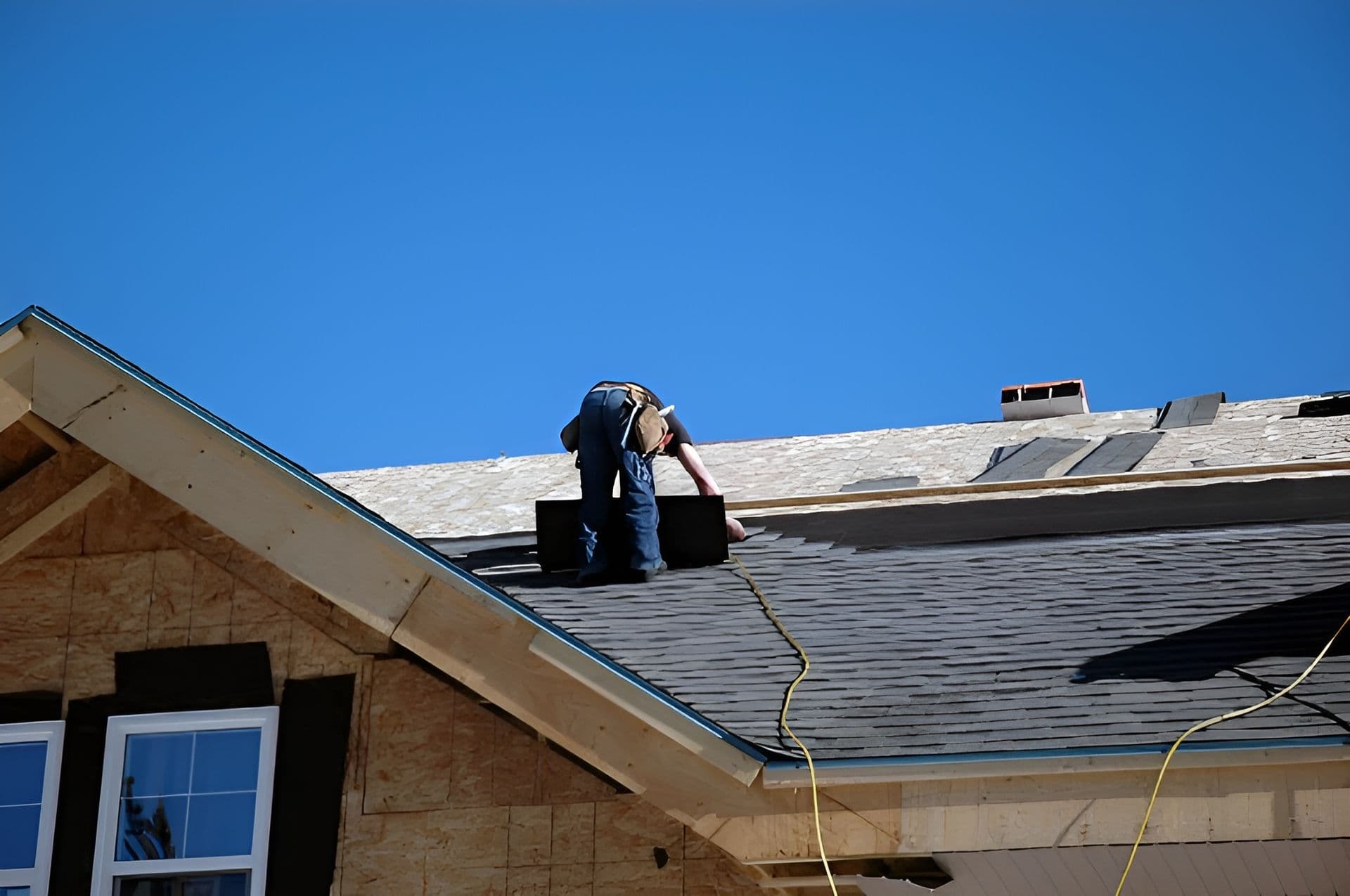 A worker installs roofing shingles.