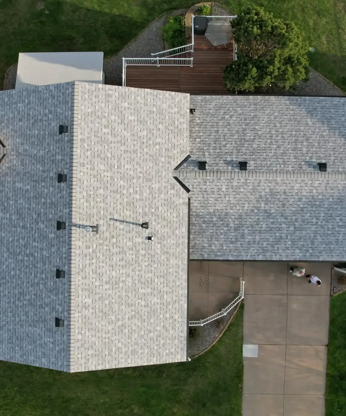 An overhead aerial view of a house with newly-installed light gray asphalt shingle roofing.