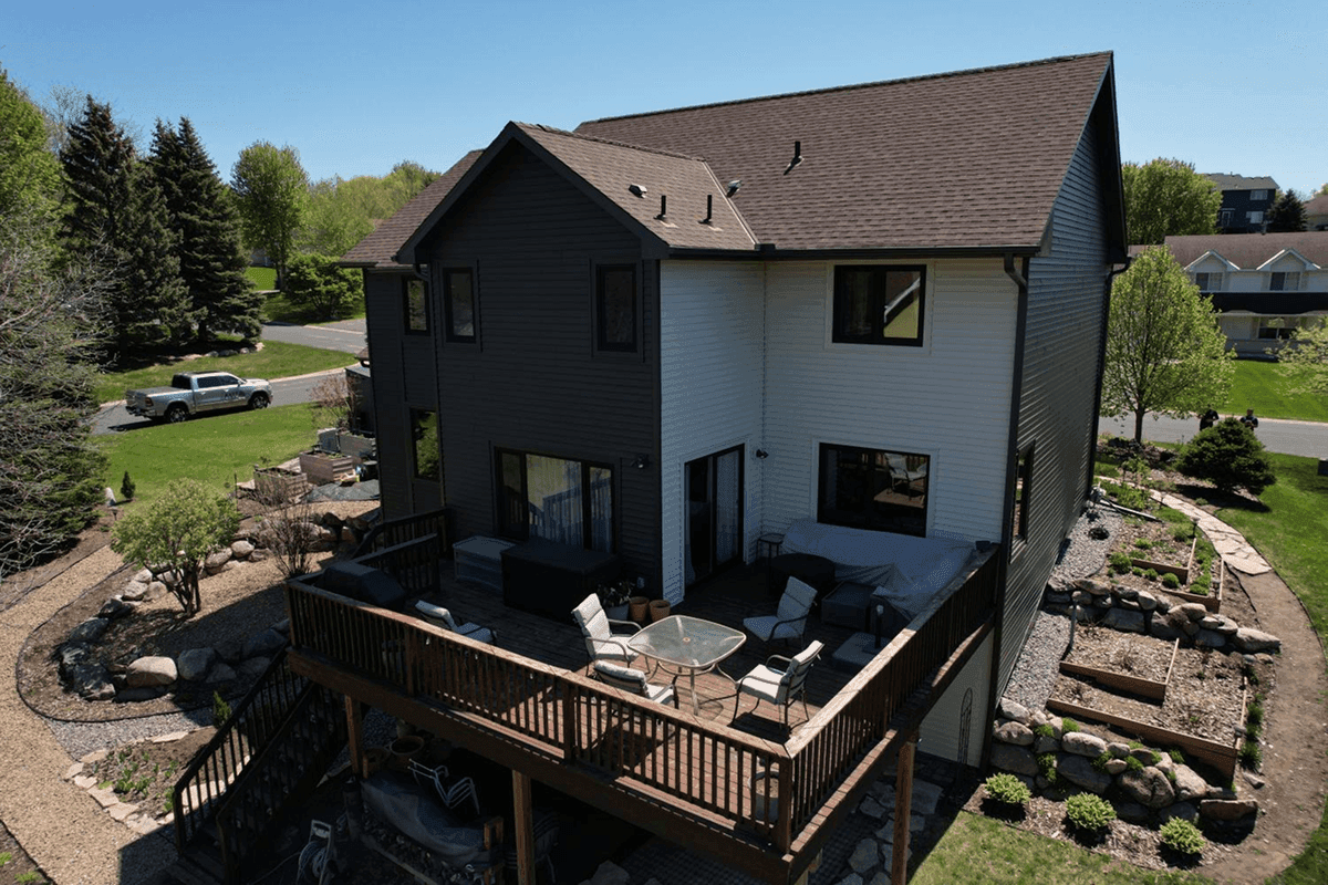 A gray and white house with a large dark brown deck.