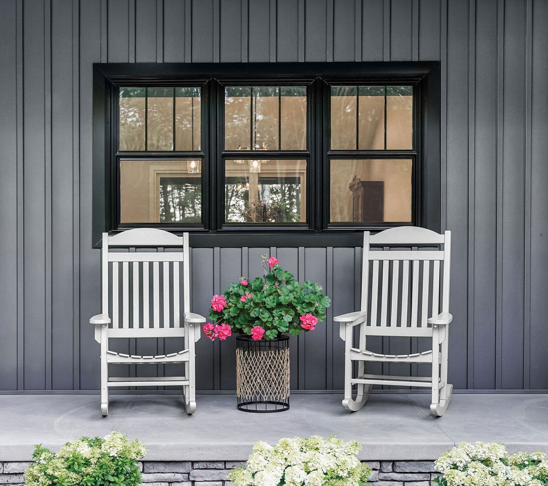 Black double-hung windows on a house with vertical gray siding.